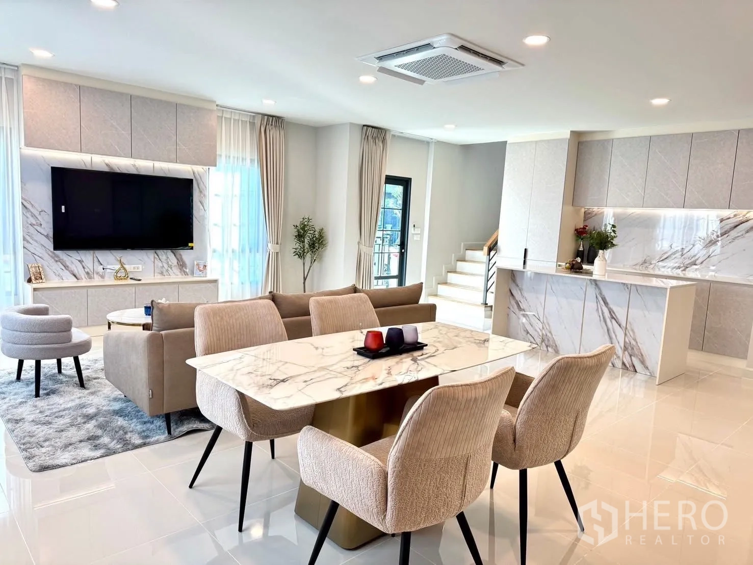 Detached House for rent in Bang Phli, Samut Prakan - Open‑plan living and dining area with marble dining table, island kitchen, and TV wall.