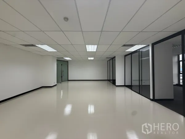 Office Space for rent - Bright collaboration or reception area with suspended ceiling lights, glass partitions, and a double glass-door entry.