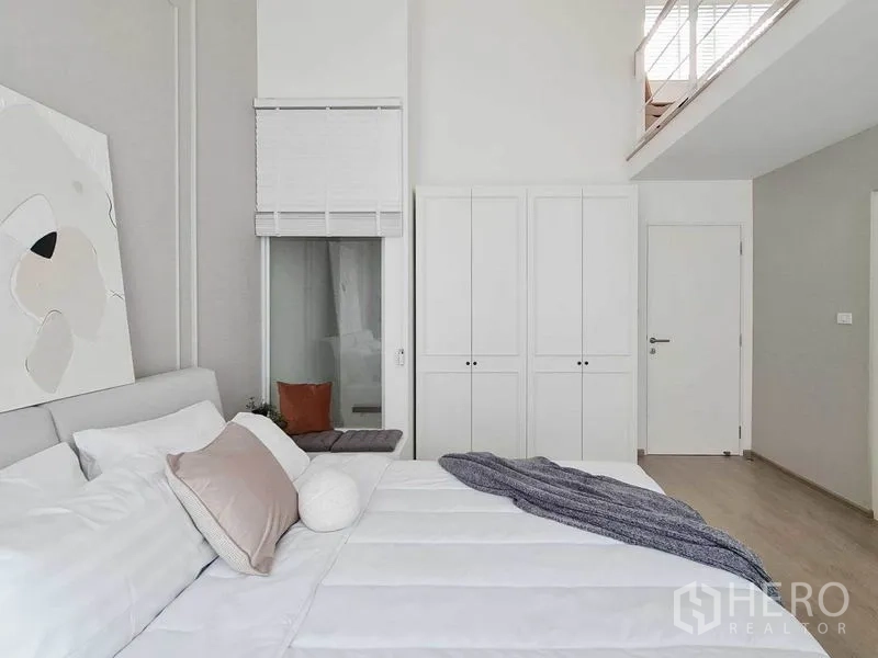 联排别墅 出租在Prawet, Bangkok - 卧室挑高空间，双门衣柜、窗边座与夹层通道。