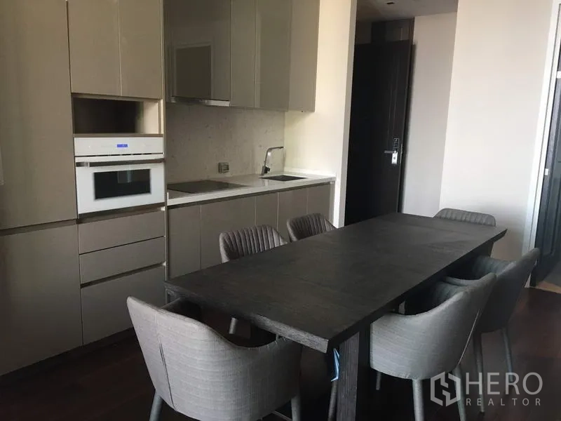 คอนโด ให้เช่าในWatthana, Bangkok - ครัวสมัยใหม่พร้อมตู้บิลต์อิน เตาอบ อ่างล้างมือ และโต๊ะทานอาหารยาวพร้อมเก้าอี้บุผ้า