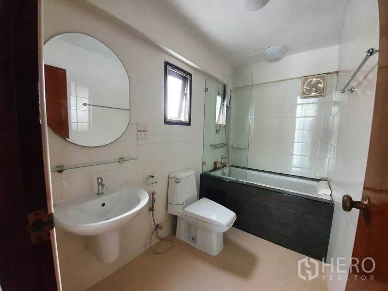 独立式住宅 出租在Phra Khanong, Bangkok - 整洁卫浴，设浴缸、玻璃隔断、小窗与白色洁具。