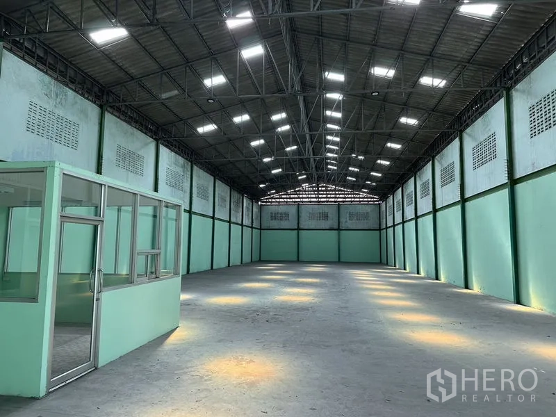Factory for rent in Bang Bo, Samut Prakan - Long interior view from the office side showing skylights and ventilation blocks along the walls.