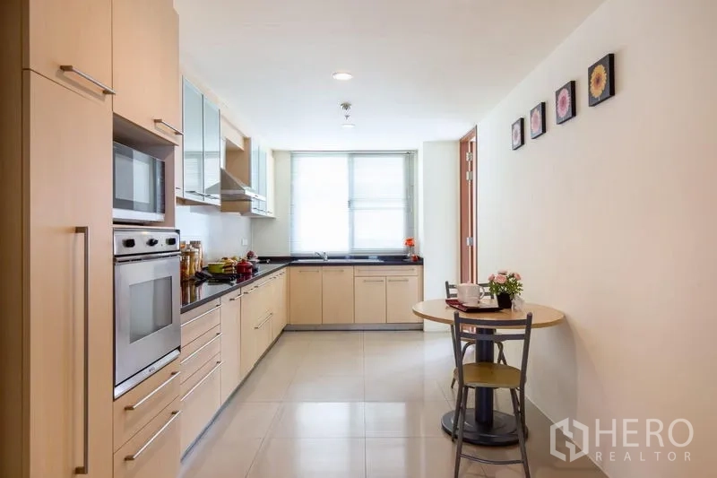 Condominium for rent in Bang Rak, Bangkok - Full-length galley kitchen with breakfast nook and a large window at the end.