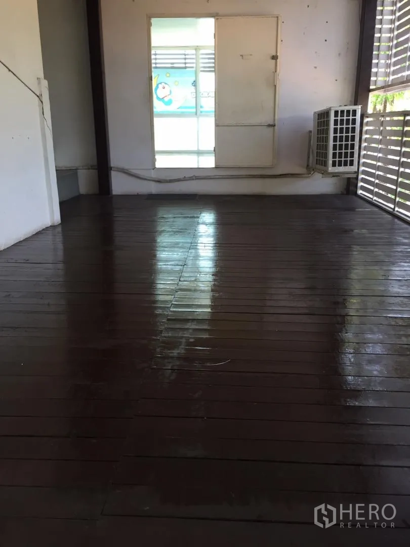 Home Office for rent or sale in Bang Khun Thian, Bangkok - Bright deck area with varnished wood flooring, wall window, and exterior AC unit.