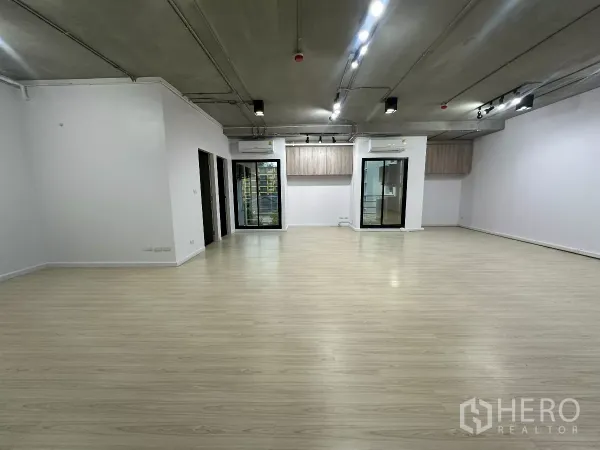 Office Space for rent in Watthana, Bangkok - Wide office hall with spotlight tracks, two glass entry doors, light timber floors and white walls.
