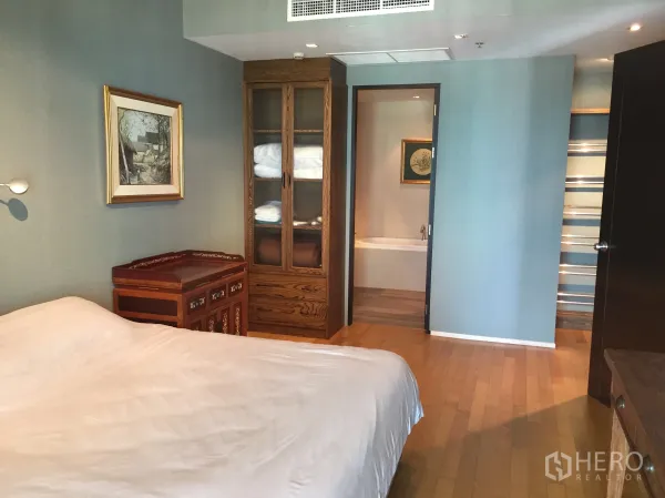 公寓 出租或出售在Watthana, Bangkok - 主卧铺木地板，设高柜与复古木桌，并有门直达套内卫浴。