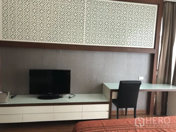 公寓 出租在Pathum Wan, Bangkok - 卧室一角，内置书桌、电视柜与装饰性镂空面板。