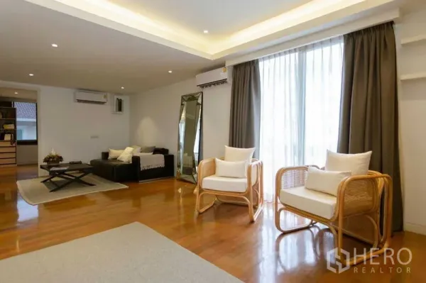 Home Office for sale in Watthana, Bangkok - Bright lounge space with seating, large window and recessed ceiling lights on wood flooring.