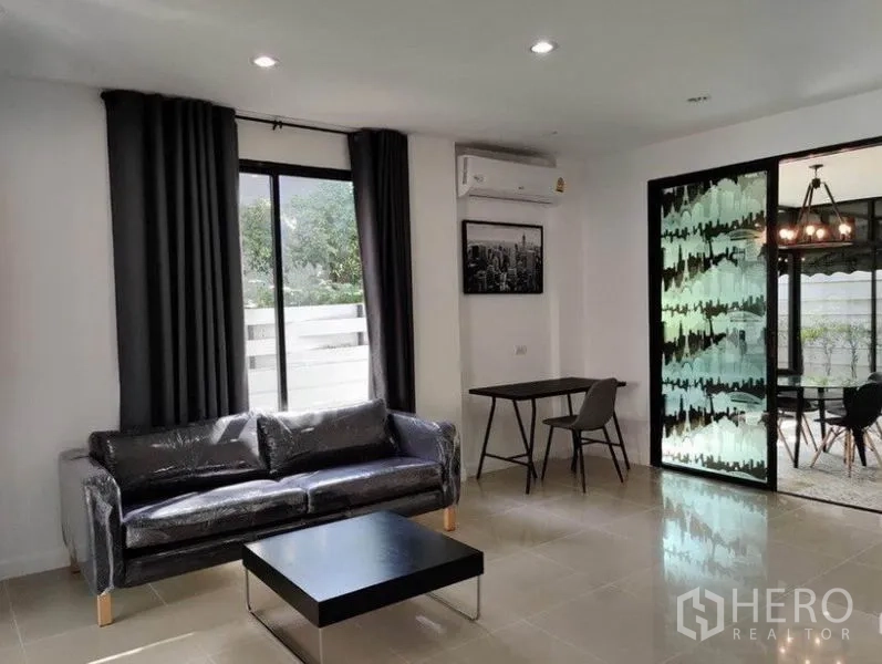 ทาวน์เฮาส์ ให้เช่าในSuan Luang, Bangkok - มุมนั่งเล่นพร้อมโซฟา โต๊ะทำงาน และวิวไปยังส่วนทานอาหารสวน