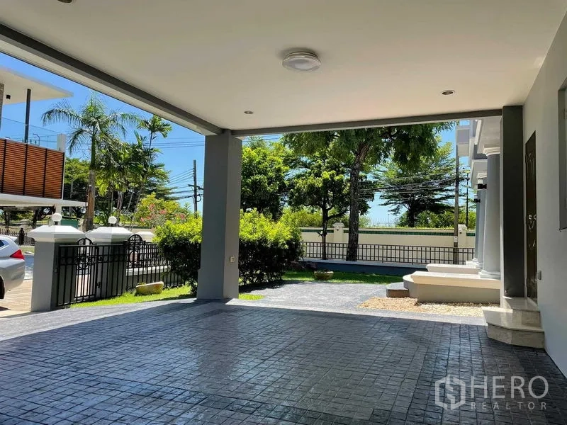 Detached House for sale in Bang Bon, Bangkok - Covered carport and paved driveway facing the gated fence and greenery