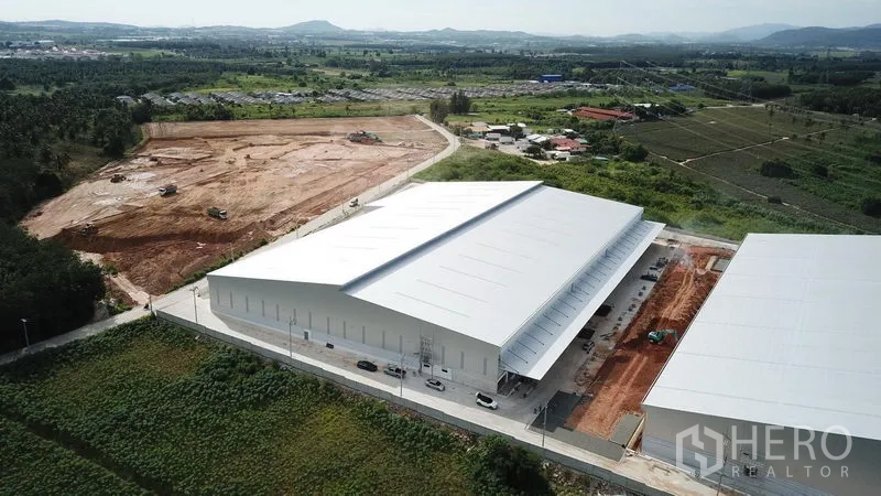 คลังสินค้า ให้เช่าในPluak Daeng, Rayong - ภาพมุมสูงของศูนย์คลังสินค้า หลังคาสีขาว ถนนทางเข้าและพื้นที่สีเขียวรอบโครงการ
