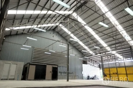 Warehouse for rent in Pak Kret, Nonthaburi - Warehouse hall featuring ventilation panels, a small utility room, and bright roof lights.