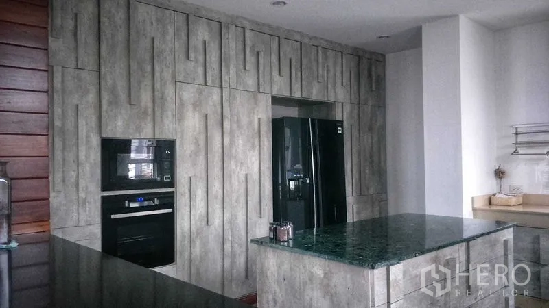 Home Office for sale in Phasi Charoen, Bangkok - Contemporary kitchen with tall built-in cabinets, black refrigerator and green stone island.