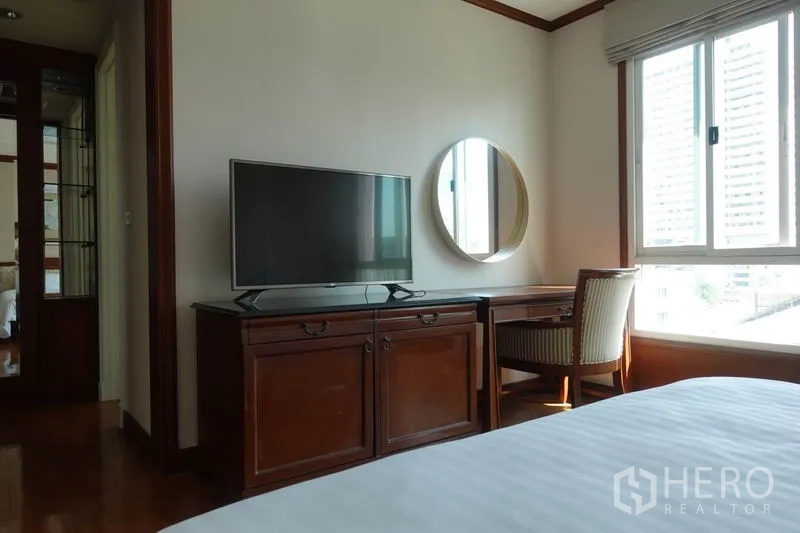 Condominium for rent in Khlong Toei, Bangkok - Bedroom corner with TV cabinet, vanity desk and large window.