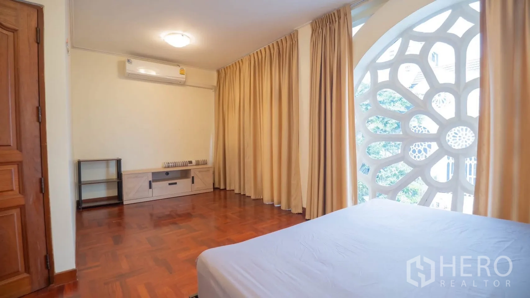 Townhouse for rent in Watthana, Bangkok - Same bedroom showing heavy curtains, air conditioner, and TV console.