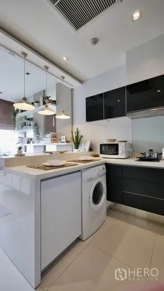 Condominium for rent or sale in Khlong Toei, Bangkok - Kitchen peninsula with pendant lights and a washing machine neatly built under the counter.