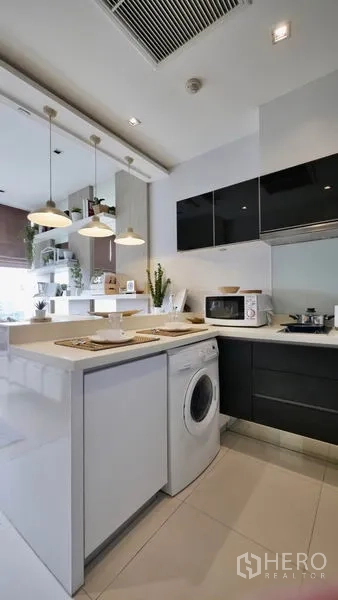 Condominium for rent or sale in Khlong Toei, Bangkok - Kitchen peninsula with pendant lights and a washing machine neatly built under the counter.