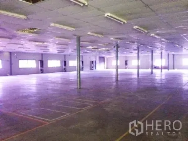 Warehouse for rent in Ban Chang, Rayong - Spacious warehouse interior with open concrete floor, support columns, windows, and fluorescent lighting.