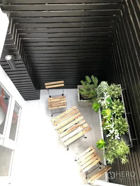 ทาวน์เฮาส์ ให้เช่าในKhlong Toei, Bangkok - ระเบียงขนาดกะทัดรัดพร้อมชุดโต๊ะไม้และสวนแนวตั้งบนผนังไม้ระแนงสีดำ