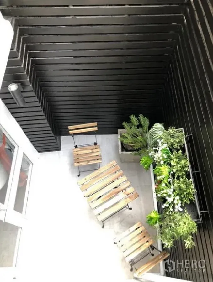 ทาวน์เฮาส์ ให้เช่าในKhlong Toei, Bangkok - ระเบียงขนาดกะทัดรัดพร้อมชุดโต๊ะไม้และสวนแนวตั้งบนผนังไม้ระแนงสีดำ