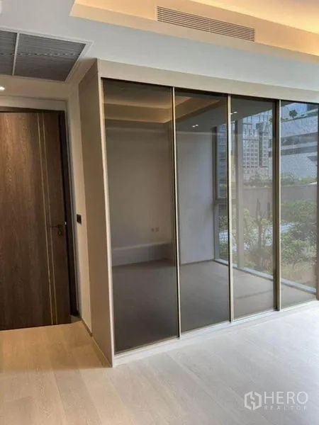 Condominium for rent in Pathum Wan, Bangkok - Bedroom featuring sliding mirrored wardrobe and wood floors.