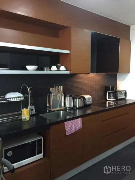 คอนโด ให้เช่าในKhlong Toei, Bangkok - ครัวแบบแกลลีย์ทันสมัย เคาน์เตอร์สีดำ ตู้บิลท์อิน เตาและเครื่องใช้ไฟฟ้า