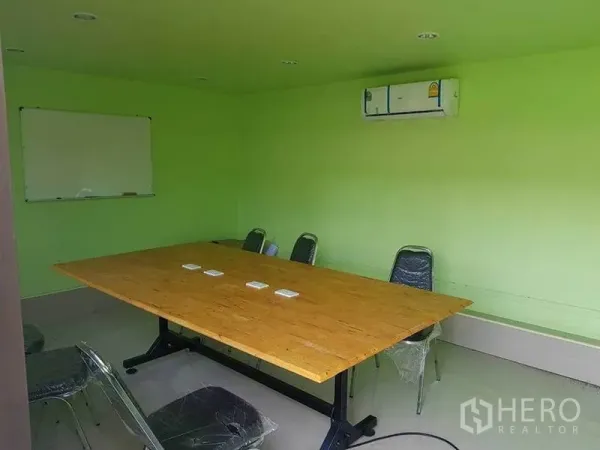 Warehouse for rent in Sai Noi, Nonthaburi - Meeting room with long table, whiteboard and wall-mounted air conditioner.