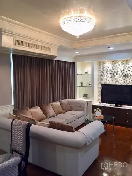 公寓 出售在Watthana, Bangkok - 起居区，转角沙发面对电视柜，展示层架与吊灯点缀。