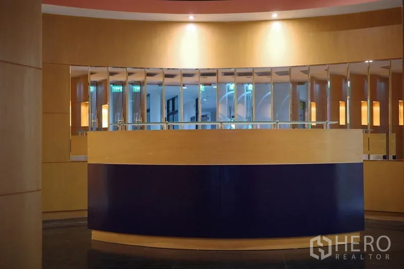 Office Space for rent in Bang Na, Bangkok - Front view of a curved reception counter with mirrored wall and warm lighting accents.