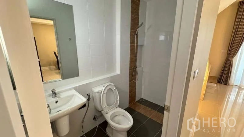 Townhouse for rent in Bang Phli, Samut Prakan - Ground-floor bathroom with shower area, toilet and large mirror.