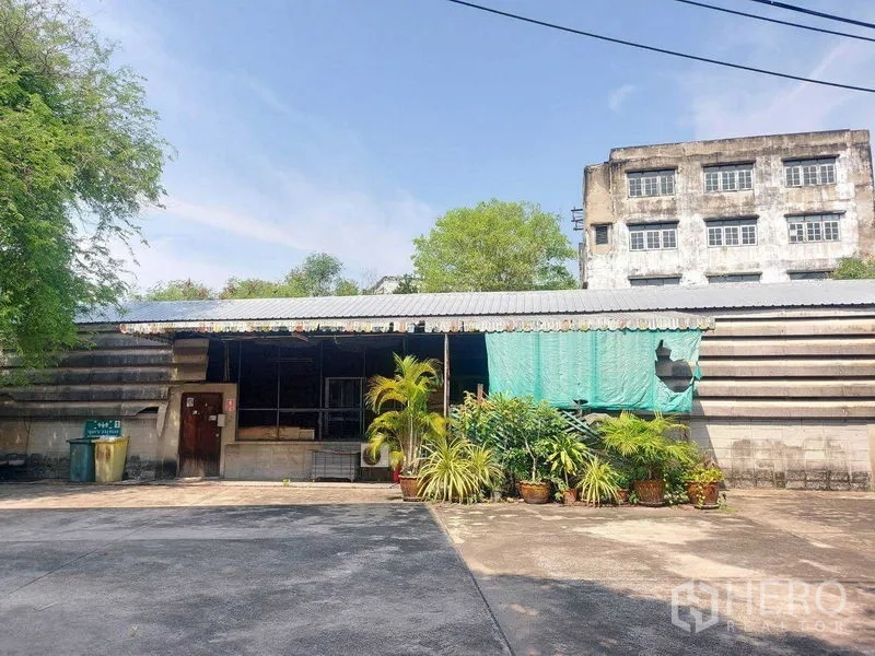 Warehouse for rent in Min Buri, Bangkok - Single-storey ancillary building with potted plants and paved service area.