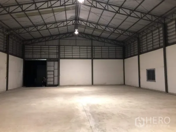 货栈 出租在Lam Luk Ka, Pathum Thani - 面向装卸门的通透库内视角，吊灯与上部通风墙体清晰可见。