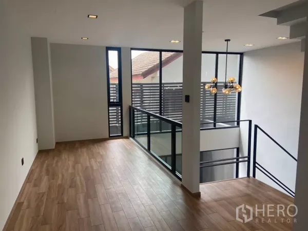 ทาวน์เฮาส์ ให้เช่าในHuai Khwang, Bangkok - โถงชั้นบนพื้นไม้ พร้อมหน้าต่างสูงจรดเพดานติดกับช่องว่างโปร่ง.