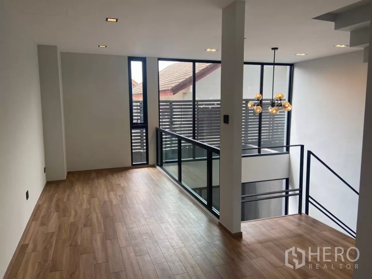 ทาวน์เฮาส์ ให้เช่าในHuai Khwang, Bangkok - โถงชั้นบนพื้นไม้ พร้อมหน้าต่างสูงจรดเพดานติดกับช่องว่างโปร่ง.