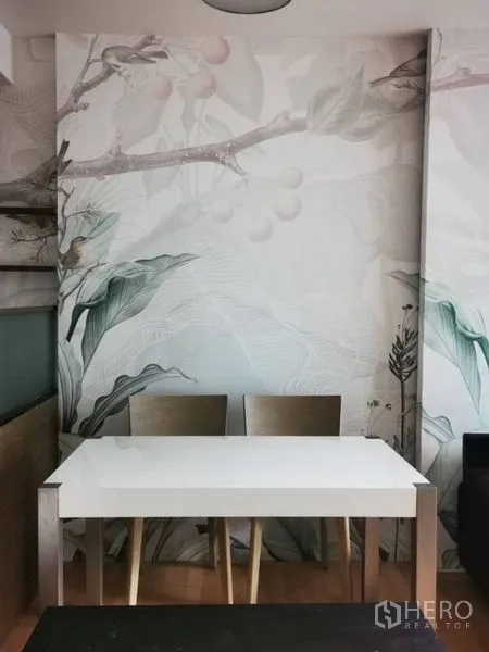 公寓 出售在Khlong Toei, Bangkok - 用餐角，白色餐桌与两把椅子，背景为植物图案墙。