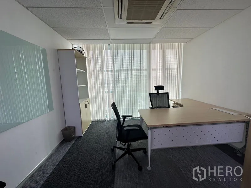Office Space for rent - Private office with large desk, ergonomic chair, carpet tiles and floor-to-ceiling windows with vertical blinds.