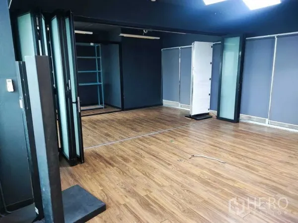 办公空间 出租在Watthana, Bangkok - 转角办公空间，深色天花、木地板与可移动玻璃隔断。