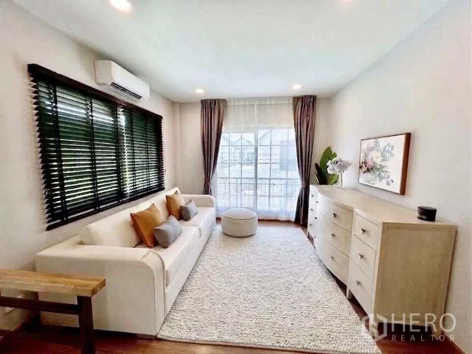 Detached House for rent in Bang Phli, Samut Prakan - Bright upstairs lounge with sofa, large window with curtains, dresser, and air conditioner.