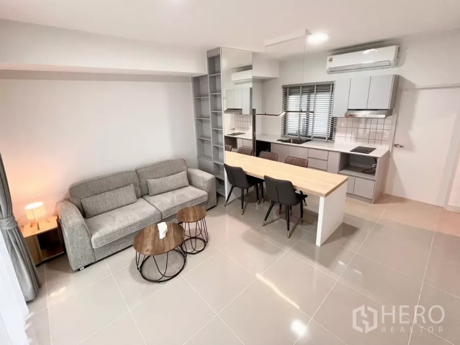 Townhouse for rent in Bang Phli, Samut Prakan - Wide view of tiled living area connected to a light grey kitchen and dining island with four chairs.