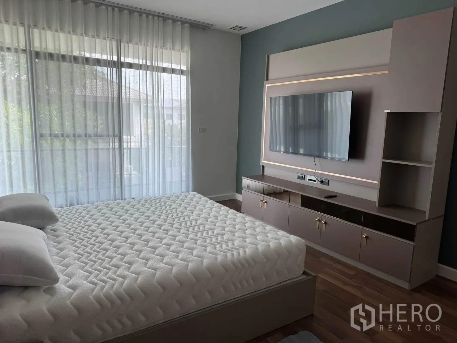 บ้านเดี่ยว for rent in Prawet, Bangkok - ผนังห้องนอนมาสเตอร์ติดทีวี บิวท์อินเก็บของ และผ้าม่านโปร่งเปิดสู่ระเบียง