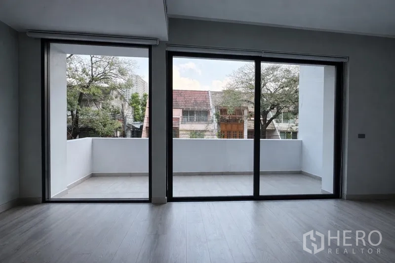 Semi-detached House for rent in Watthana, Bangkok - Living area with floor-to-ceiling sliding doors opening to a wide balcony.