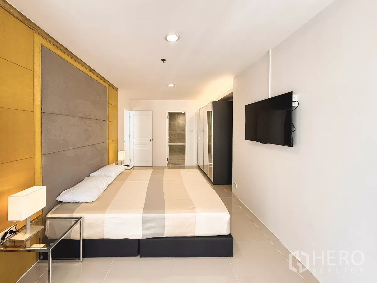 公寓 出租在Khlong Toei, Bangkok - 主卧配墙挂电视、床头板，并有套内卫浴入口。