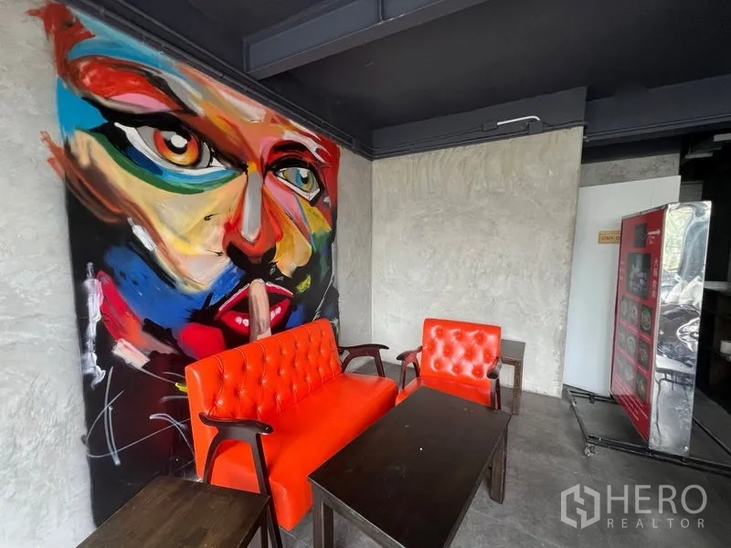 พื้นที่ขายปลีก ให้เช่าในWatthana, Bangkok - มุมที่นั่งโซฟาและเก้าอี้สีส้ม ข้างภาพวาดแนวศิลป์.