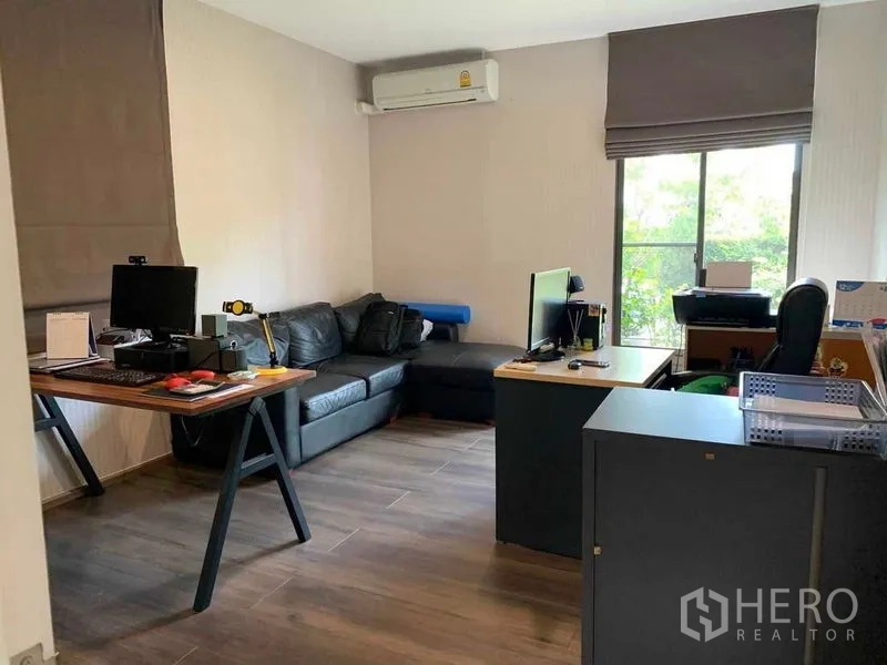 Detached House for rent or sale in Bang Phli, Samut Prakan - Home office room with desks, computers, black sectional sofa, air conditioner and window.