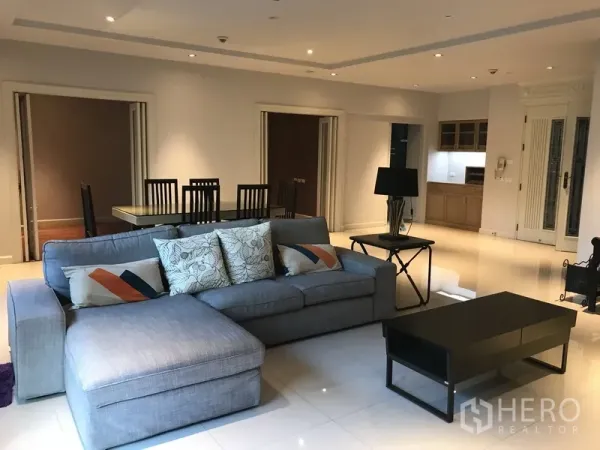 Apartment for rent in Pathum Wan, Bangkok - Spacious lounge with L-shaped sofa, dining table and compact adjacent kitchen.