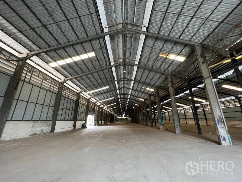 Warehouse for rent in Phra Samut Chedi, Samut Prakan - Deep-span warehouse hall with ridge skylights and expansive empty floor.