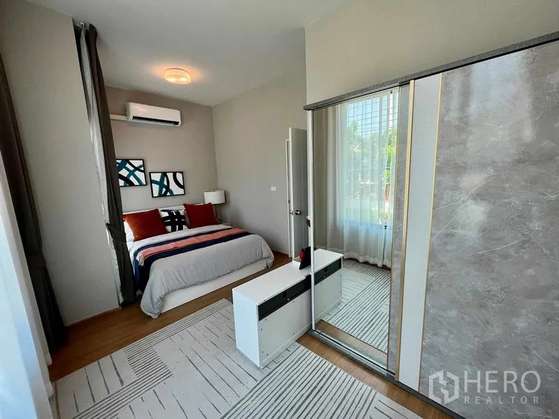 Townhouse for sale in Sai Mai, Bangkok - Spacious master bedroom with mirrored wardrobe, air conditioner, and floor-to-ceiling windows.