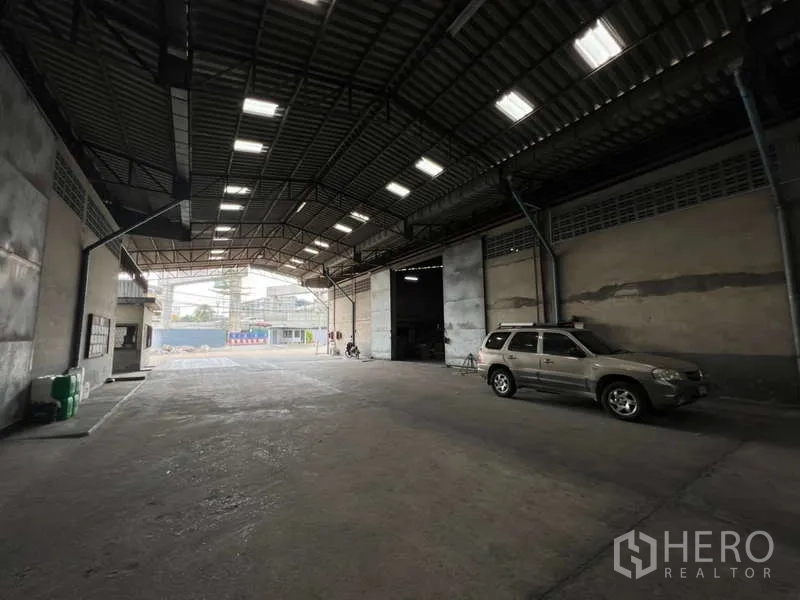 Warehouse for rent - Covered warehouse loading bay with high steel roof, skylights and concrete floor, car parked at the side.