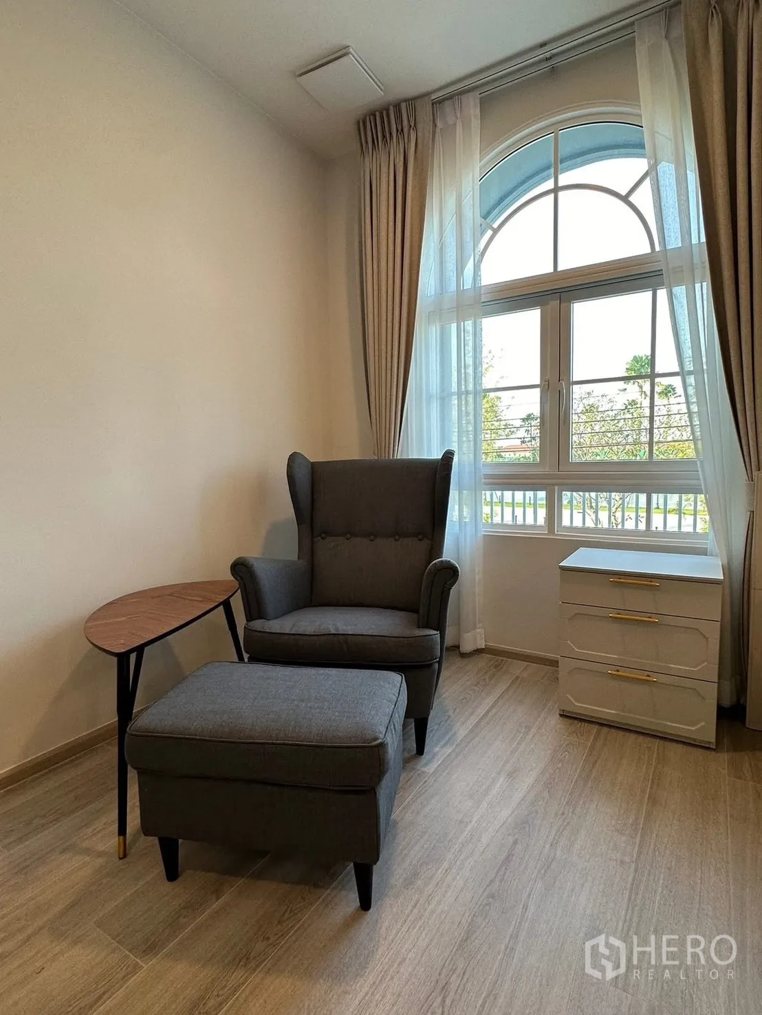 Detached House for rent in Bang Phli, Samut Prakan - Reading corner with armchair and ottoman by the arched window.