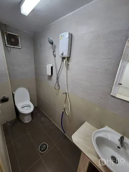 Home Office for rent in Khlong Toei, Bangkok - Bathroom featuring a toilet, handheld shower with water heater, sink, and ventilation fan.